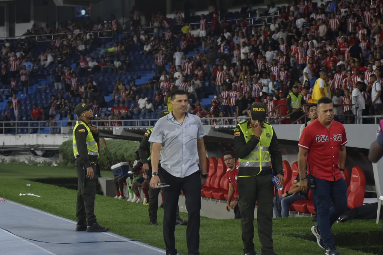 El técnico con los aficionados molestos en el fondo. 