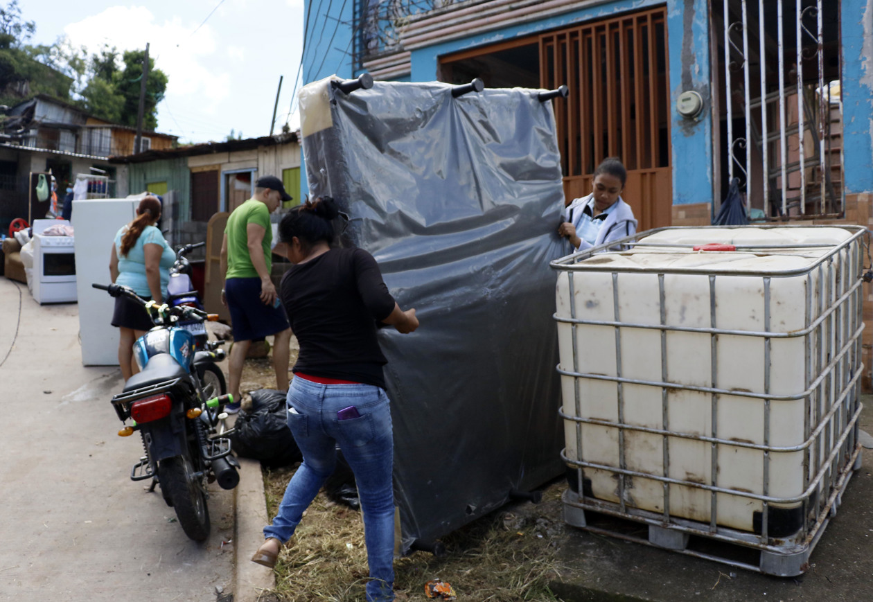 Personas tratan de rescatar sus pertenencias tras presentarse fallas estructurales en sus casas por las fuertes lluvias.