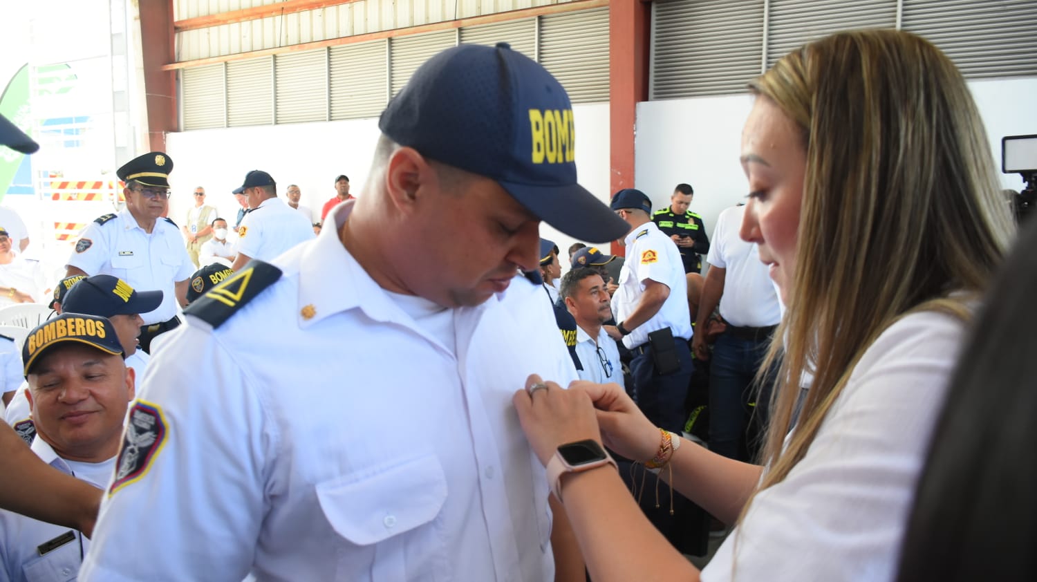 La Secretaria de Gobierno Jennifer Villarreal coloca un distintivo a un bombero.