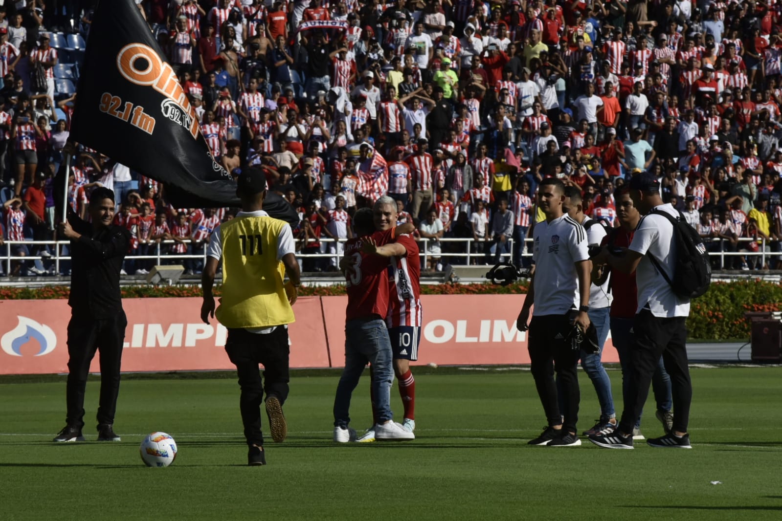 El volante creativo de Junior, Juan Fernando Quintero, abrazando a un hincha que saltó al terreno de juego.