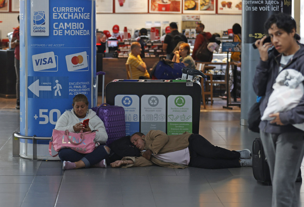 Personas esperan hoy, en el aeropuerto El Dorado de Bogotá.