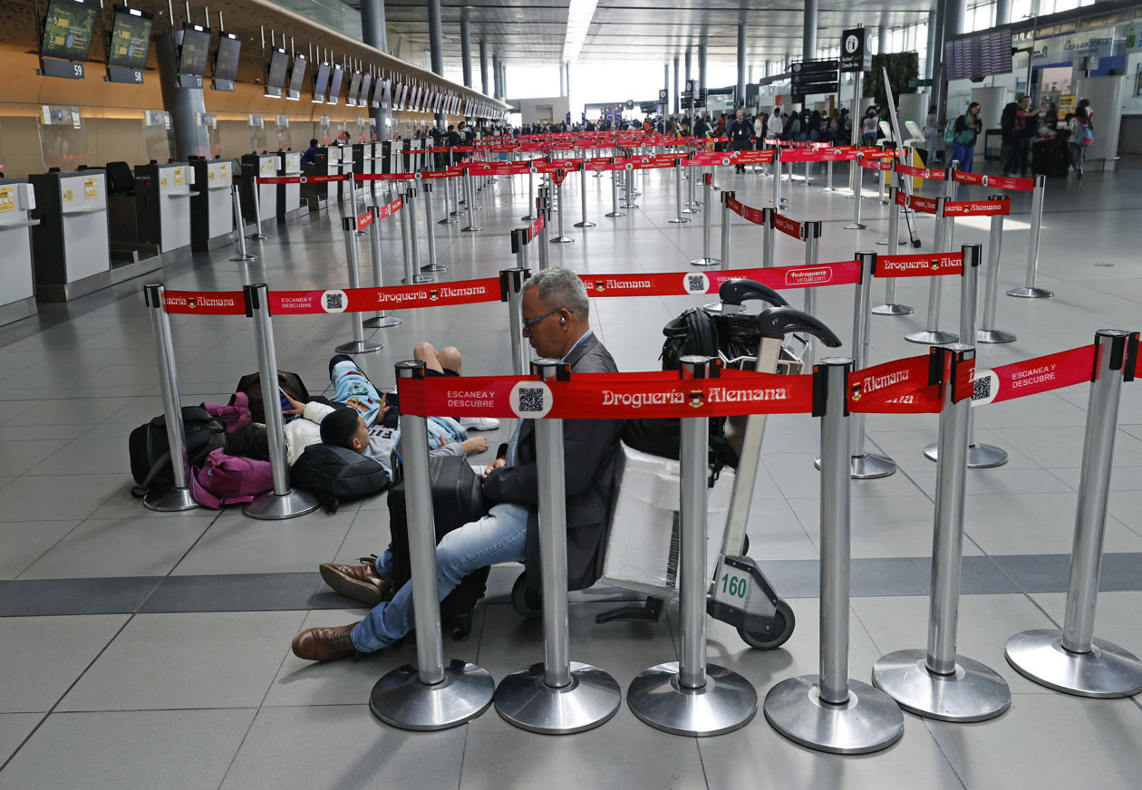 Personas esperan hoy, en el aeropuerto El Dorado de Bogotá.