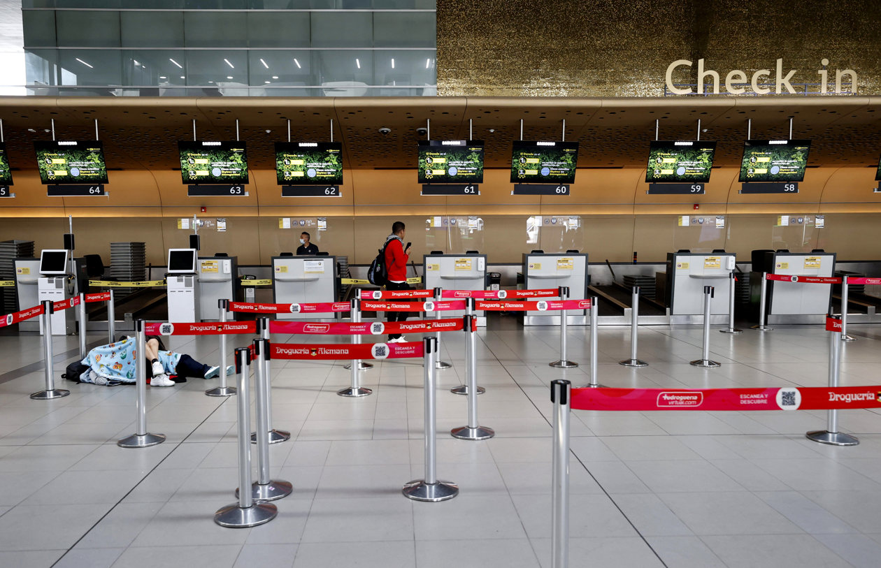 Personas esperan hoy, en el aeropuerto El Dorado de Bogotá.