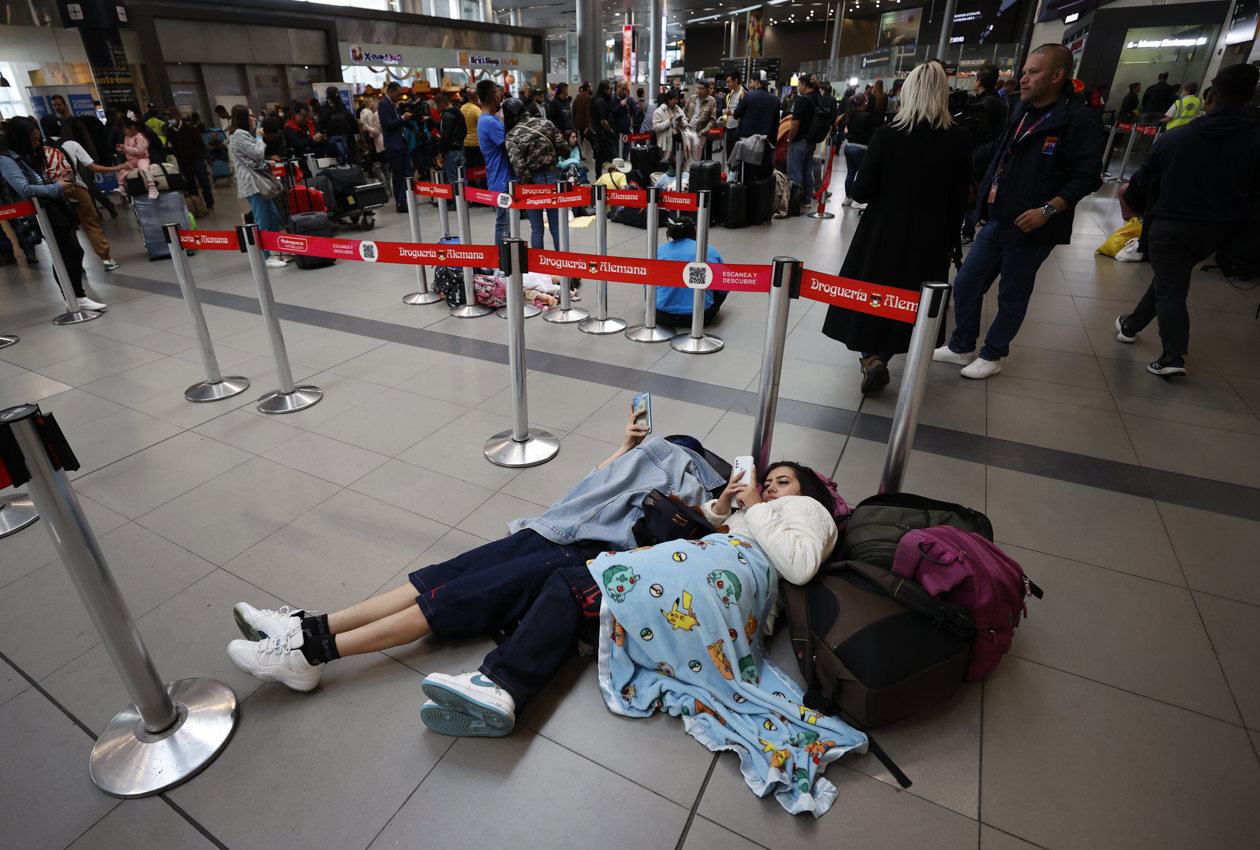 Personas esperan hoy, en el aeropuerto El Dorado de Bogotá.