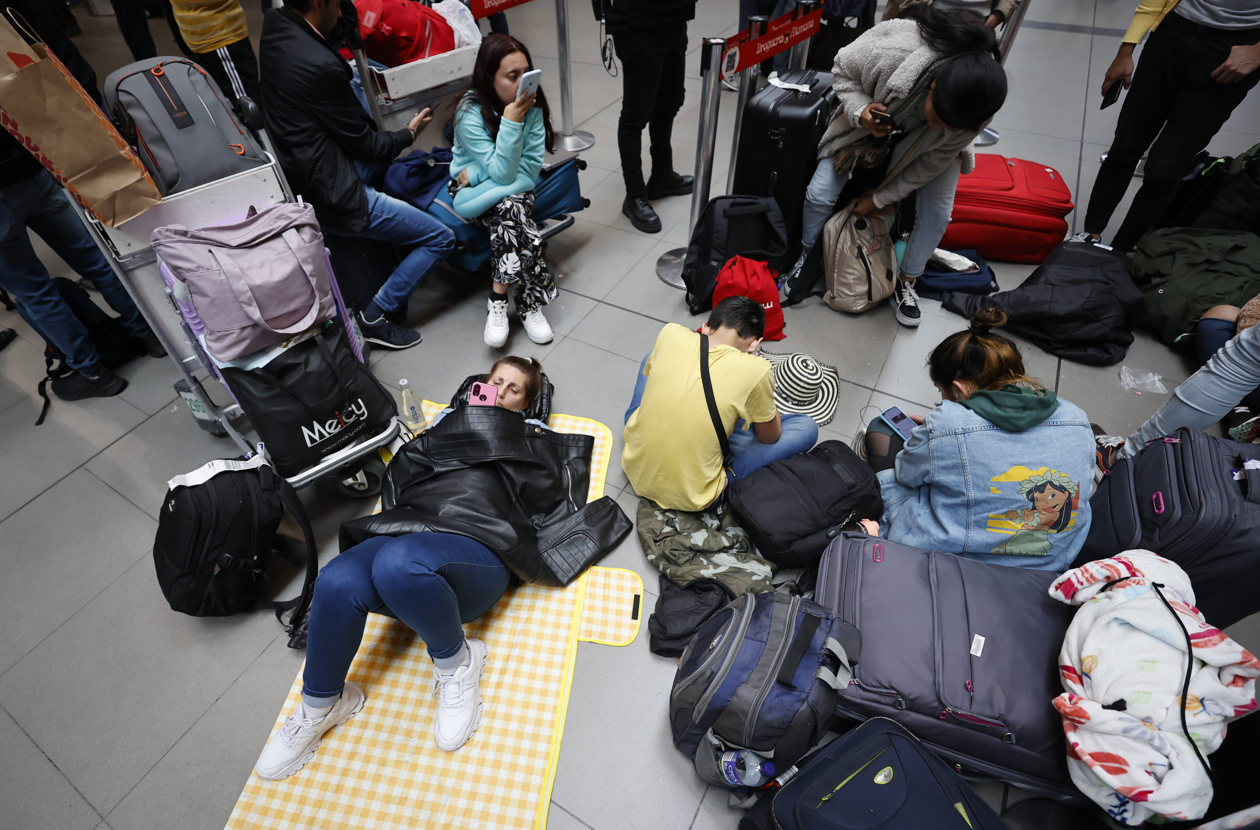 Personas esperan hoy, en el aeropuerto El Dorado de Bogotá.