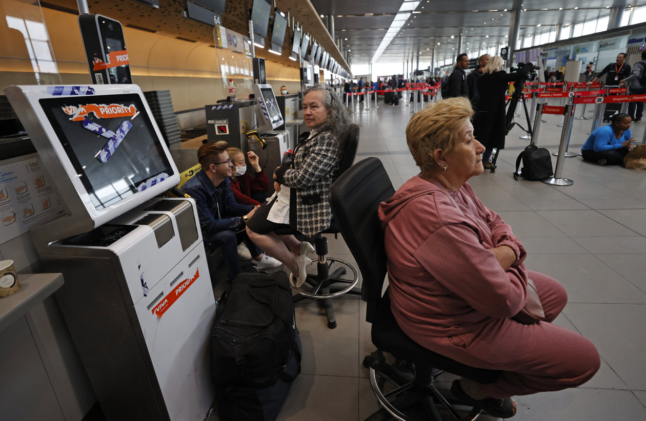 Personas esperan hoy, en el aeropuerto El Dorado de Bogotá.