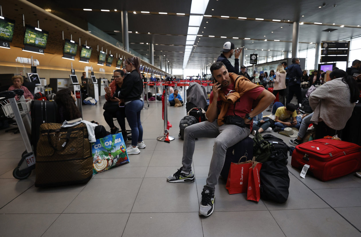 Personas esperan hoy, en el aeropuerto El Dorado de Bogotá.