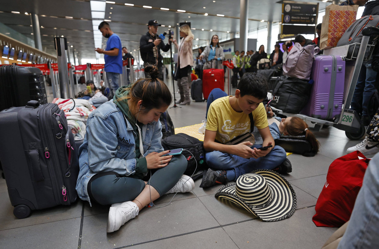 Personas esperan hoy, en el aeropuerto El Dorado de Bogotá.