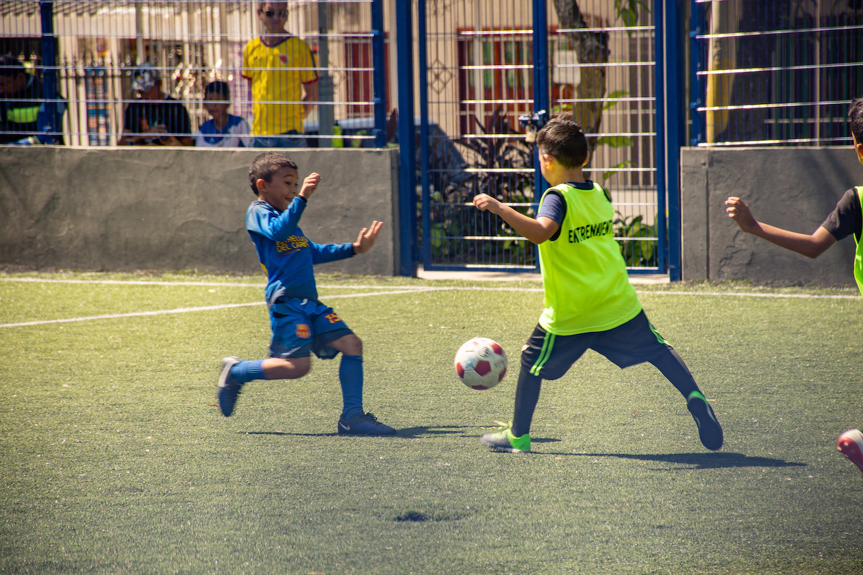 Niños disfrutando en la cancha de fútbol.