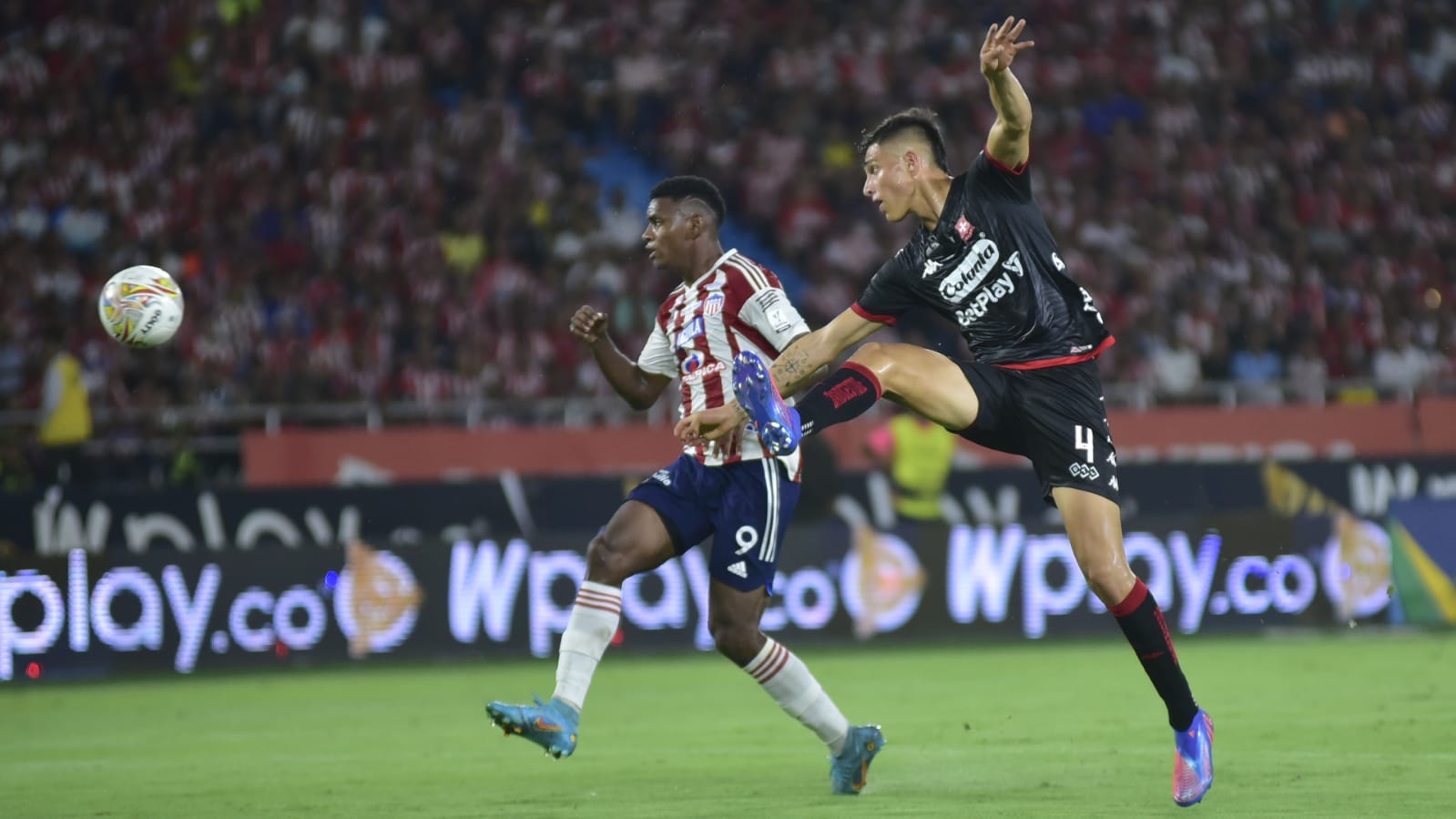 David Ramírez despejando un balón ante el acoso de Brayan León.