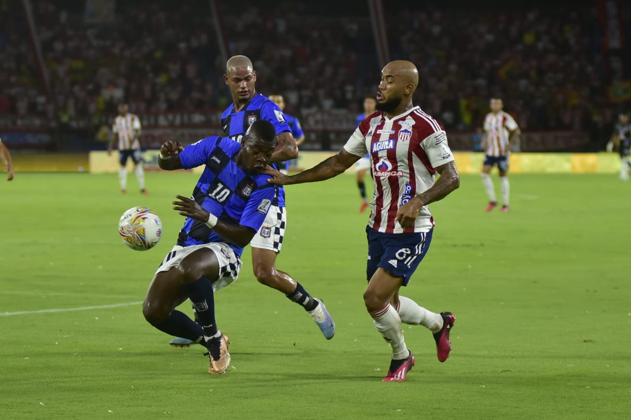 Fredy Hinestroza intentando llegar entre dos rivales.