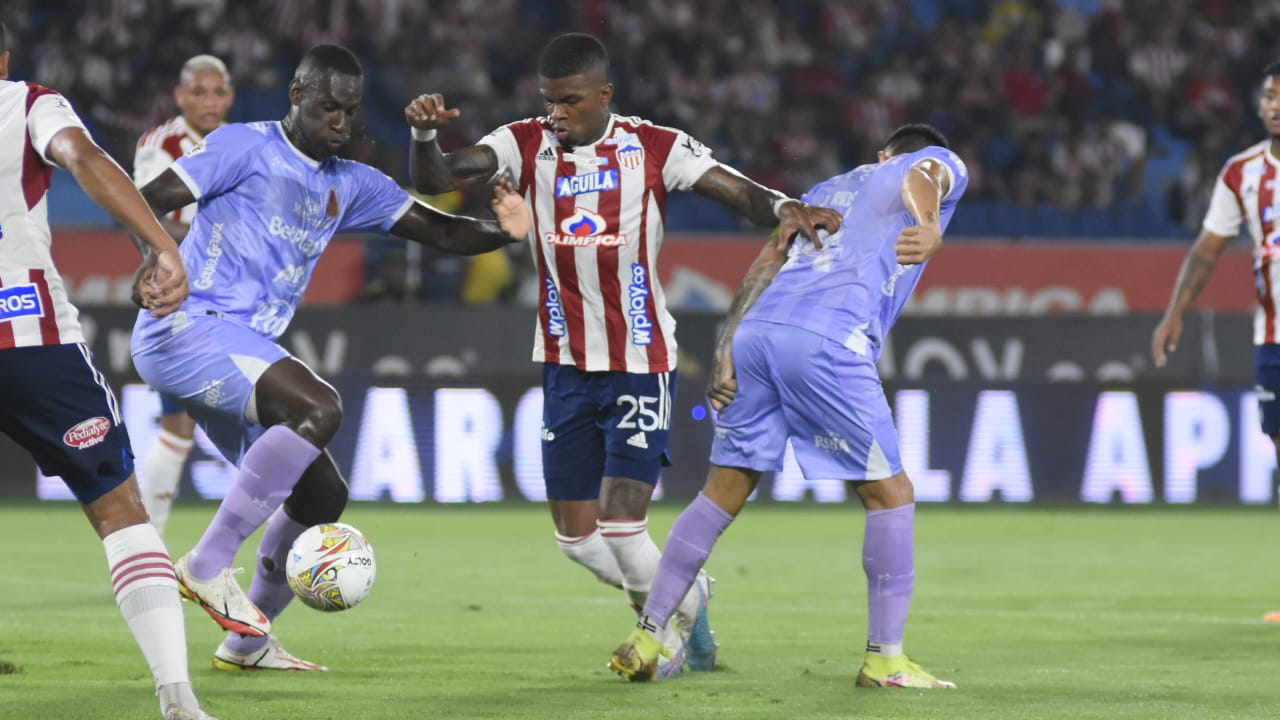 Brayan Ceballos intenta pasar entre dos jugadores rivales.