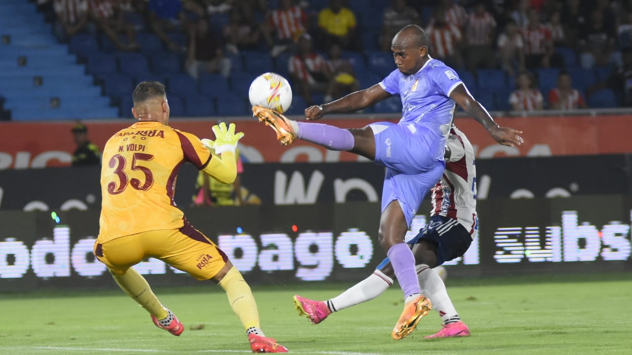 Junior Hernández despeja ante la presión de Déiber Caicedo. 