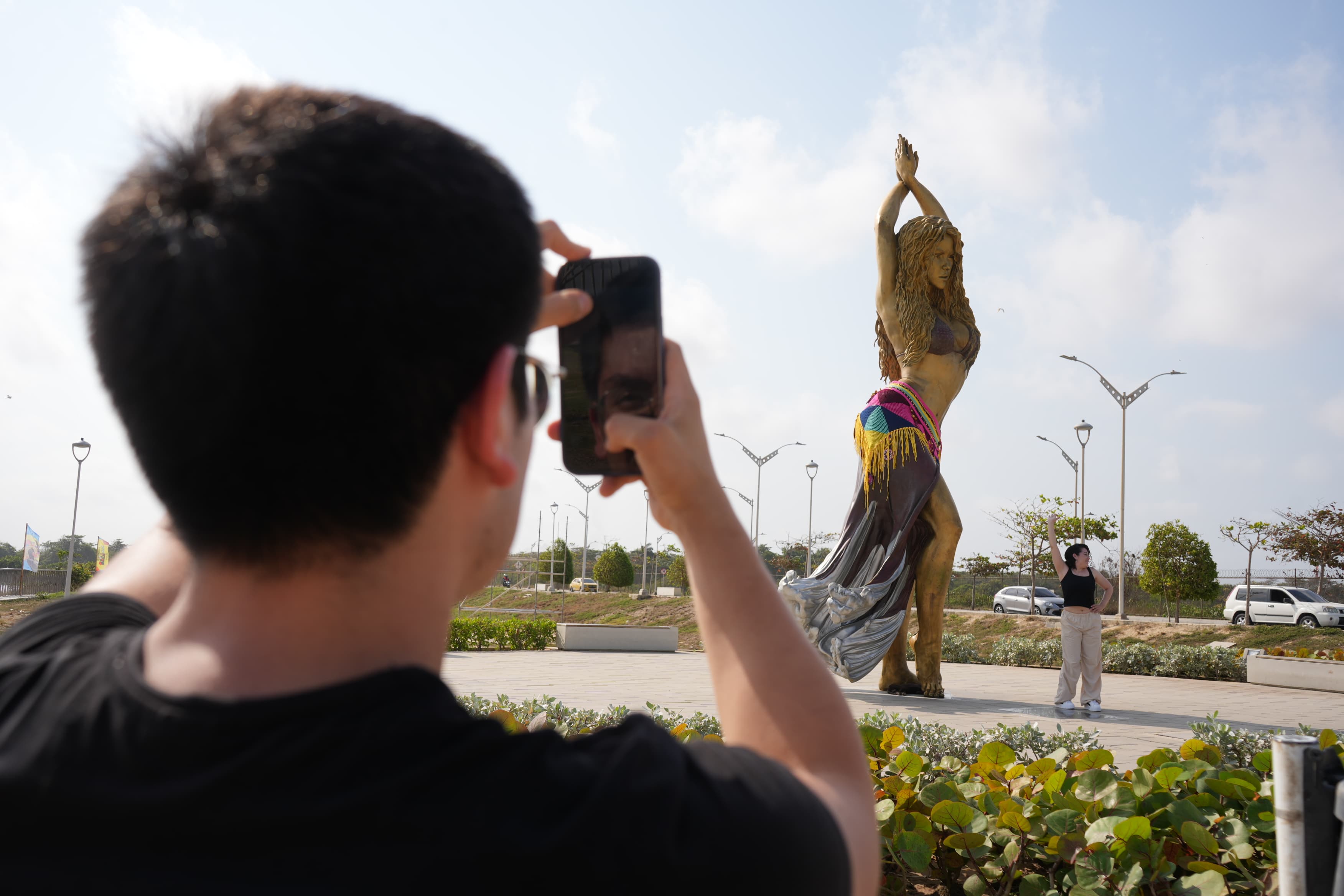 Turista en la estatua de Shakira en el Malecón del Río.