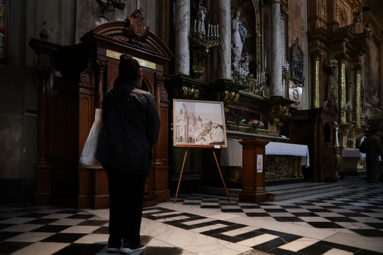 Una mujer se para frente al confesionario que muestra una imagen del Papa Francisco en la Basílica de San José de las Flores de Buenos Aires.