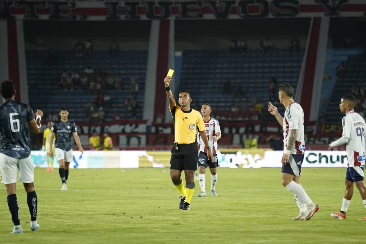 Árbitro Mauricio Mercado sacando una amarilla en el duelo.