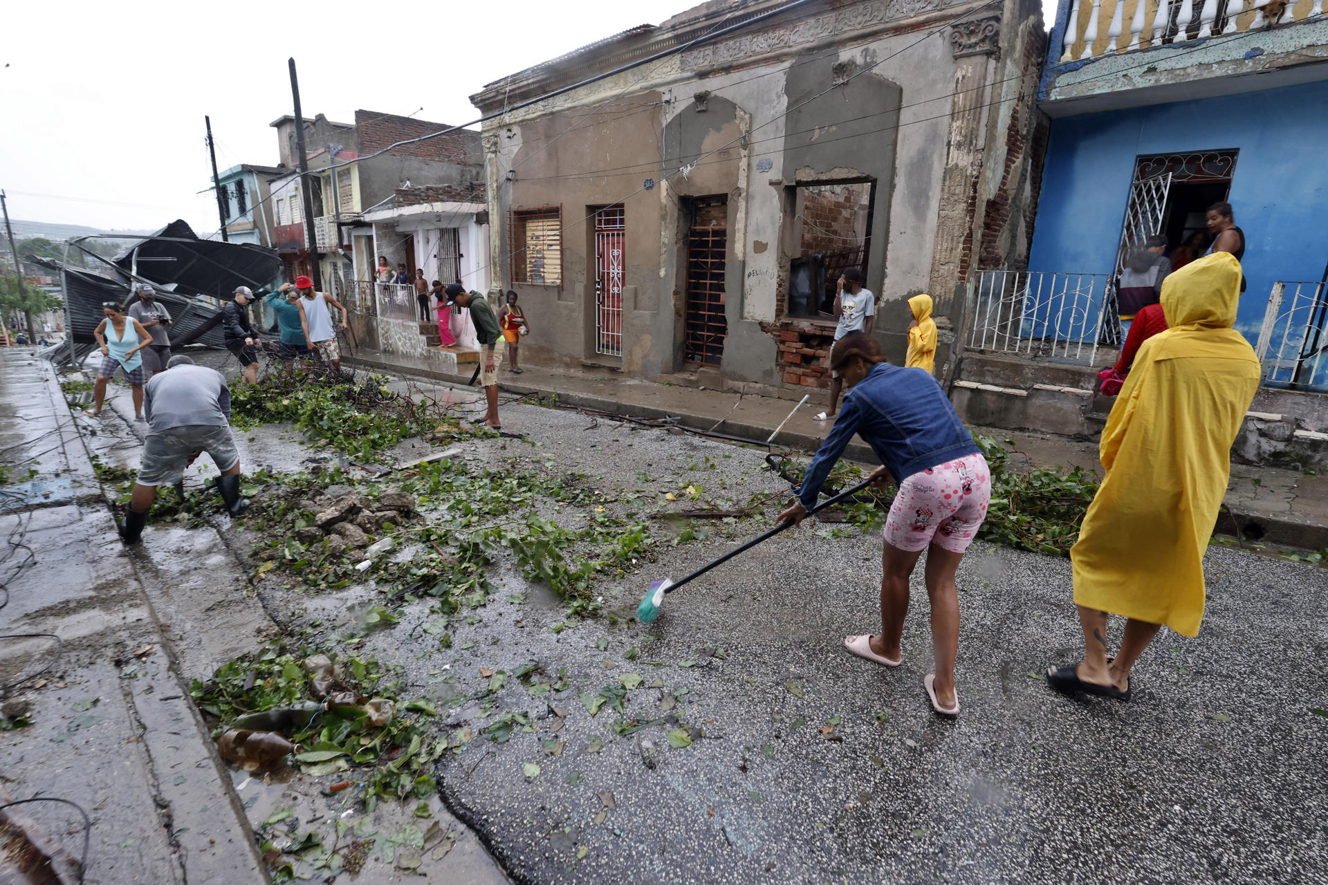 Personas recogen escombros en una calle afectada por el paso del huracán Melissa este miércoles, en Santiago de Cuba.