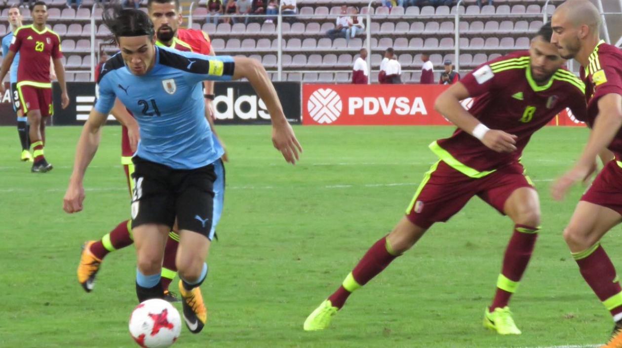 Edinson Cavani intenta eludir la marca de dos venezolanos.