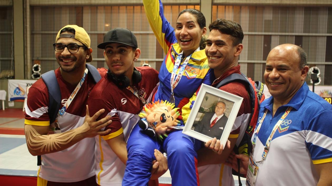 Compañeros del equipo de esgrima de Venezuela levantan a María Martínez (c) luego de ser premiada con la medalla de oro