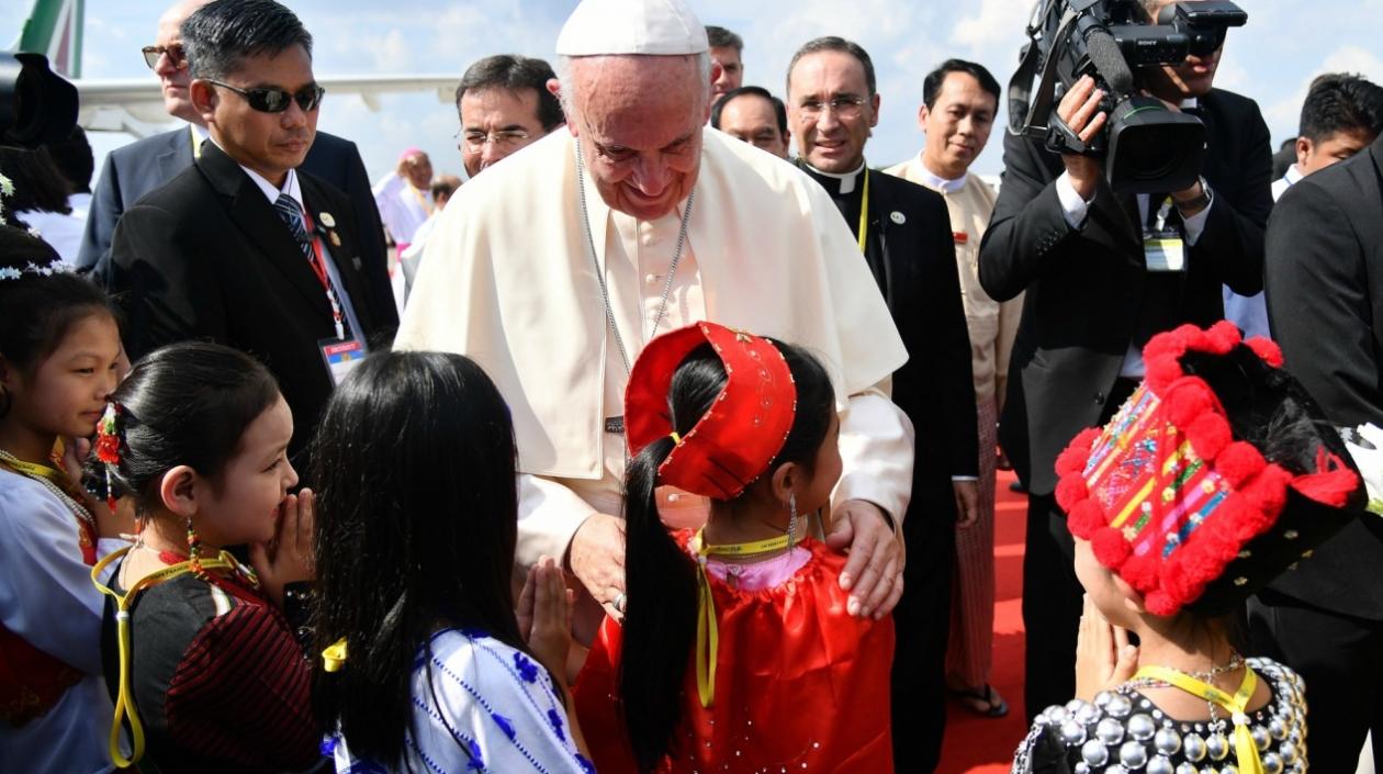El papa Francisco saluda a un grupo de niños vestidos con trajes tradicionales a su llegada al aeropuerto internacional de Rangún, Birmania.