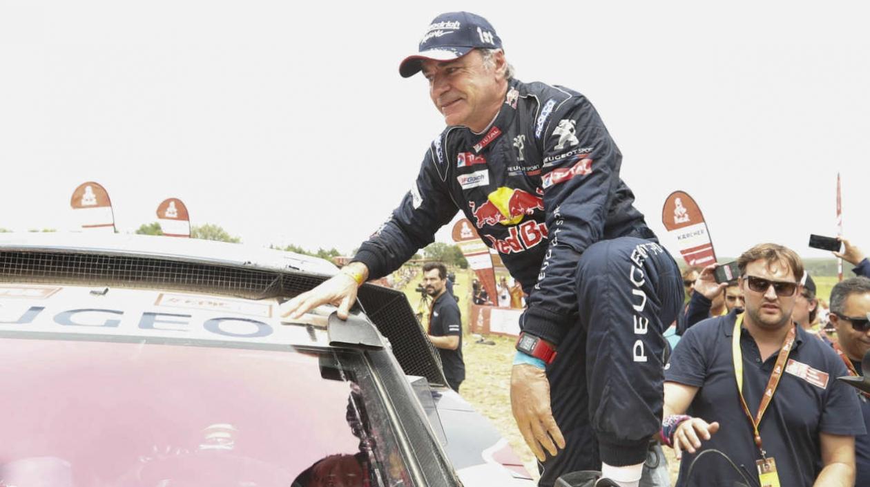 Carlos Saiz sube al techo de su vehículo para festejar su triunfo. 