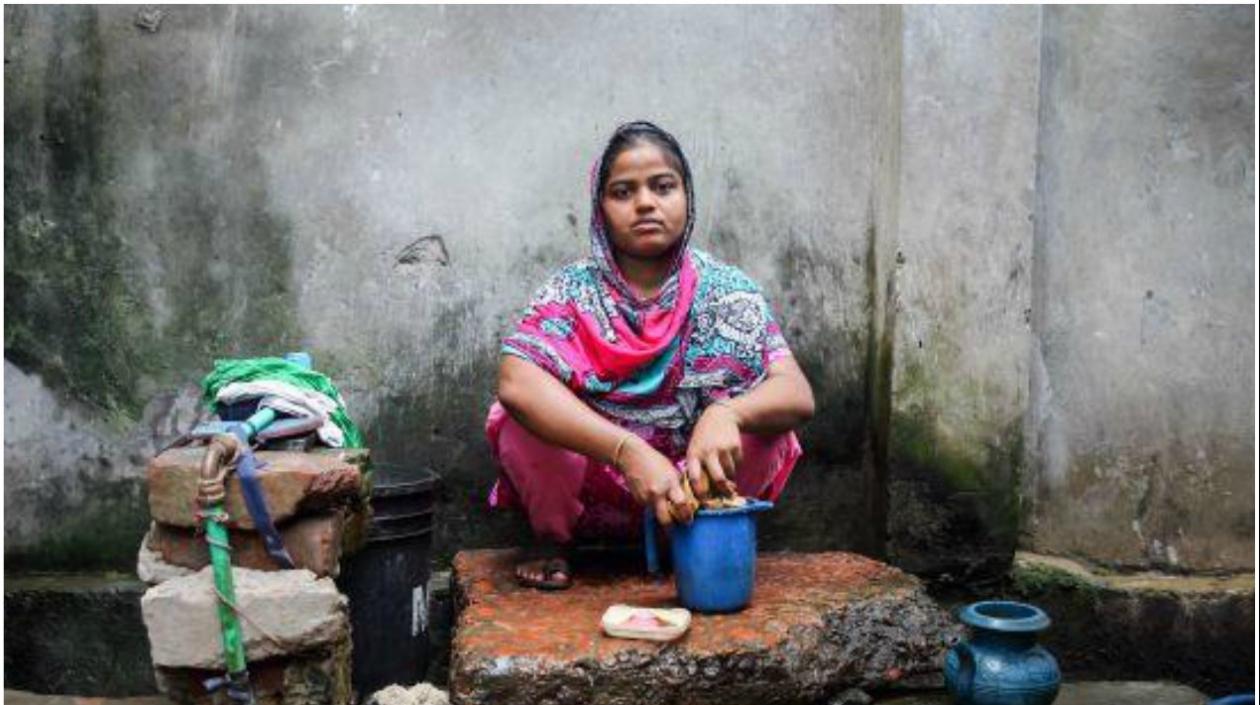 Rasheda, madre de dos niños, lava ropa en la parte trasera de su casa, cerca de una cloaca, en Chittagong (Bangladesh).