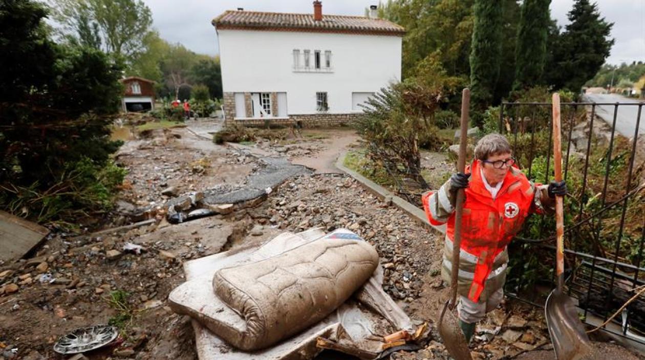 Una voluntaria de la Cruz Roja despeja una calle de escombros tras las inundaciones provocadas por las fuertes lluvias en el departamento de Aude, en Conques (Francia).