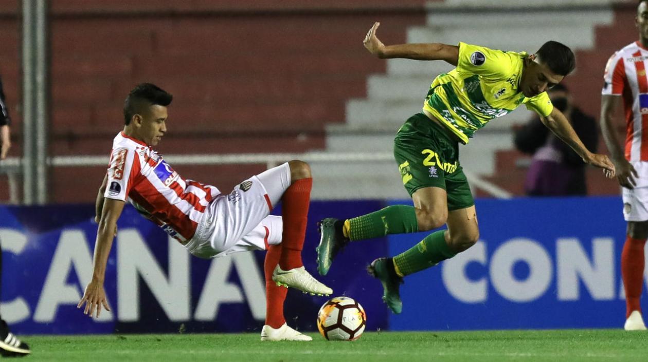 Víctor Cantillo disputa la pelota con un jugador de Defensa y Justicia. 