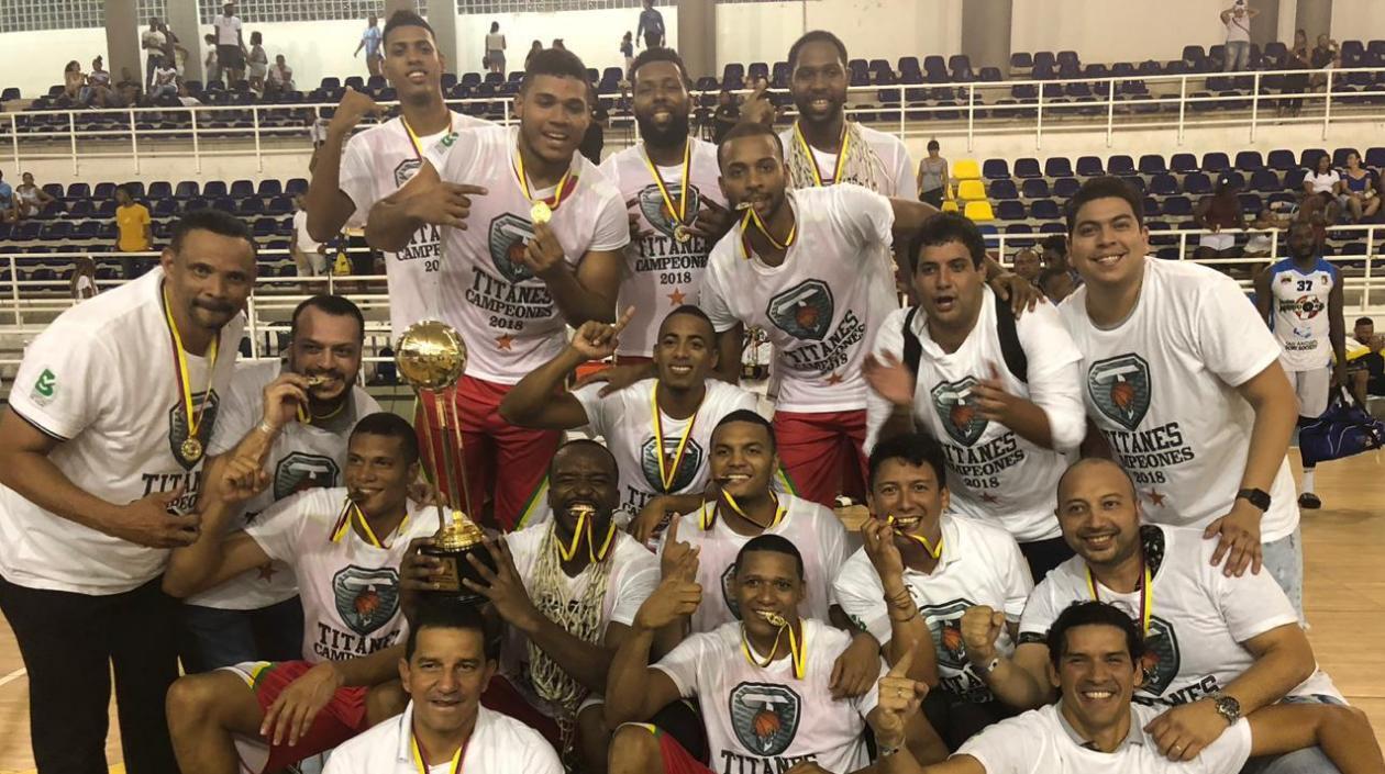 Xavier Roberson sostiene el trofeo de campeón mientras que sus compañeros celebran el título.