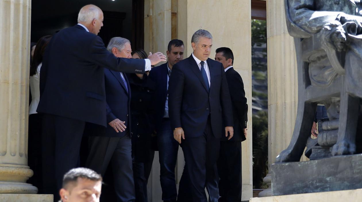 El presidente de Colombia, Iván Duque (c), sale de la Academia Colombiana de la Lengua, lugar de velación del expresidente Belisario Betancur