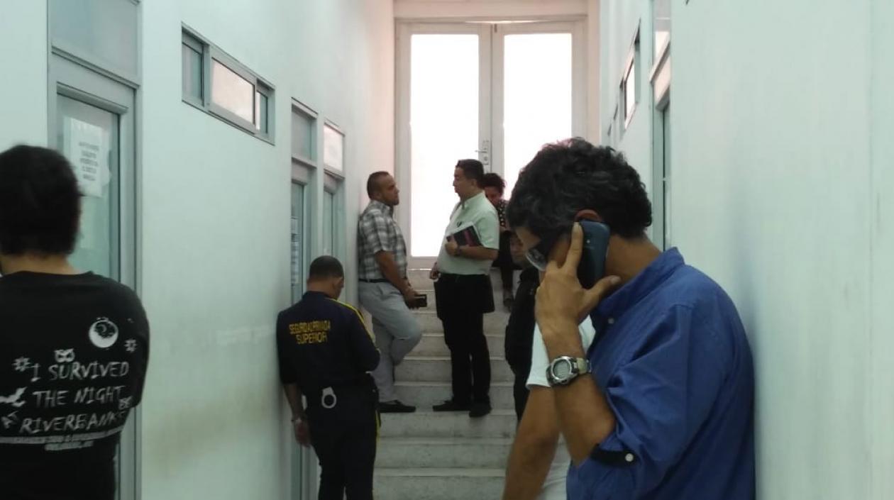 El taxista, al fondo, recostado sobre la pared.