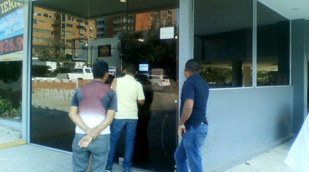 Gente mira a través del vidrio, donde un hombre joven que trabajaba como celador fue hallado muerto.