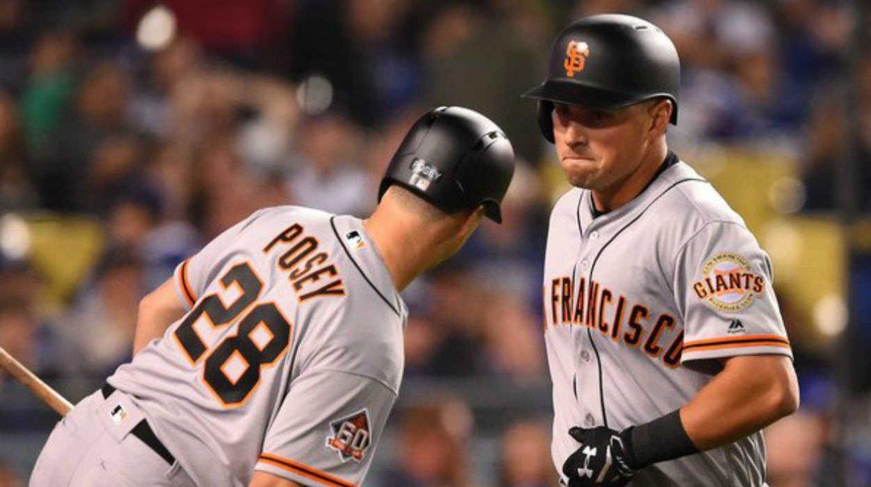 Joe Panik celebra tras su cuadrangular con Buster Posey. 