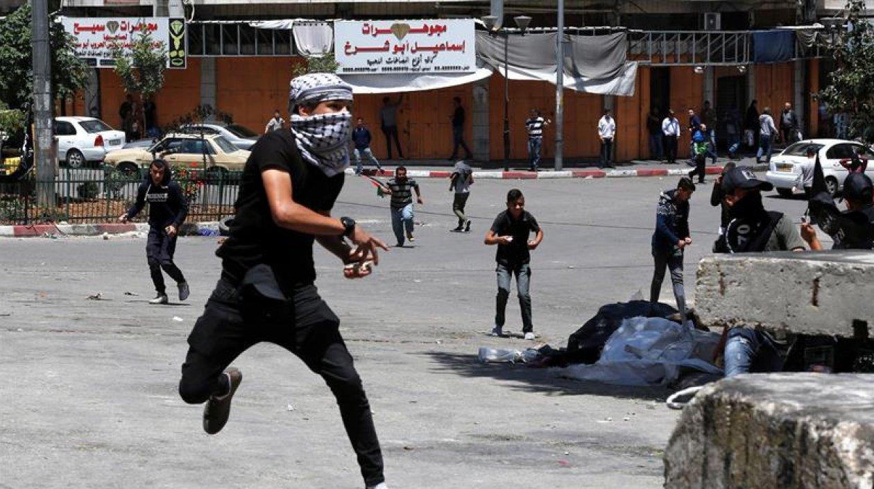 Un palestino arroja piedras contra las tropas israelíes durante un enfrentamiento en la ciudad cisjordana de Hebrón.