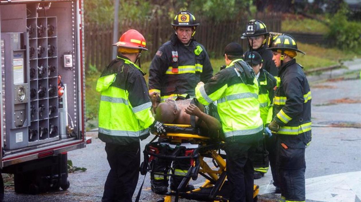 Trabajadores de los equipos de rescate trasladan a un hombre herido tras la caída de un árbol en su vivienda.