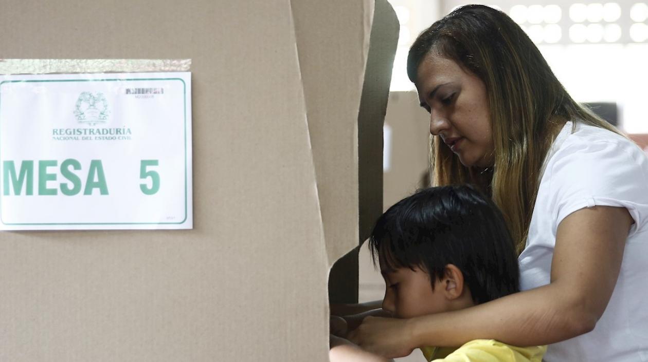 Una mujer vota con su hijo en Medellín.