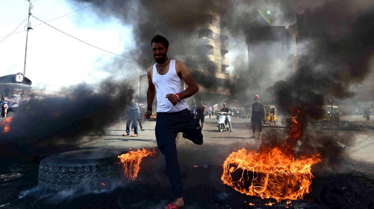 Un manifestante corre entre llantas ardiendo durante una manifestación en la plaza de Khillani en Bagdad, Irak.