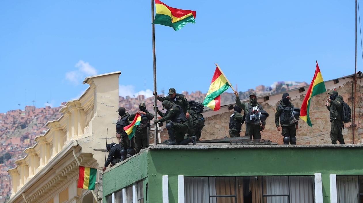 Policías de La Paz se manifiestan con banderas bolivianas luego de replegarse este sábado a una unidad de esa fuerza cercana a la plaza Murillo.