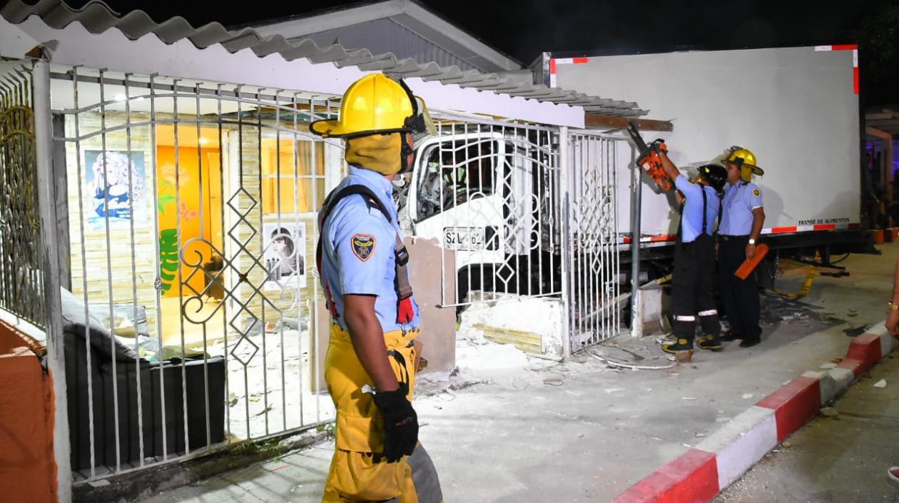 Bomberos trabajan en la extracción del camión que quedó aprisionado entre las rejas de la casa.