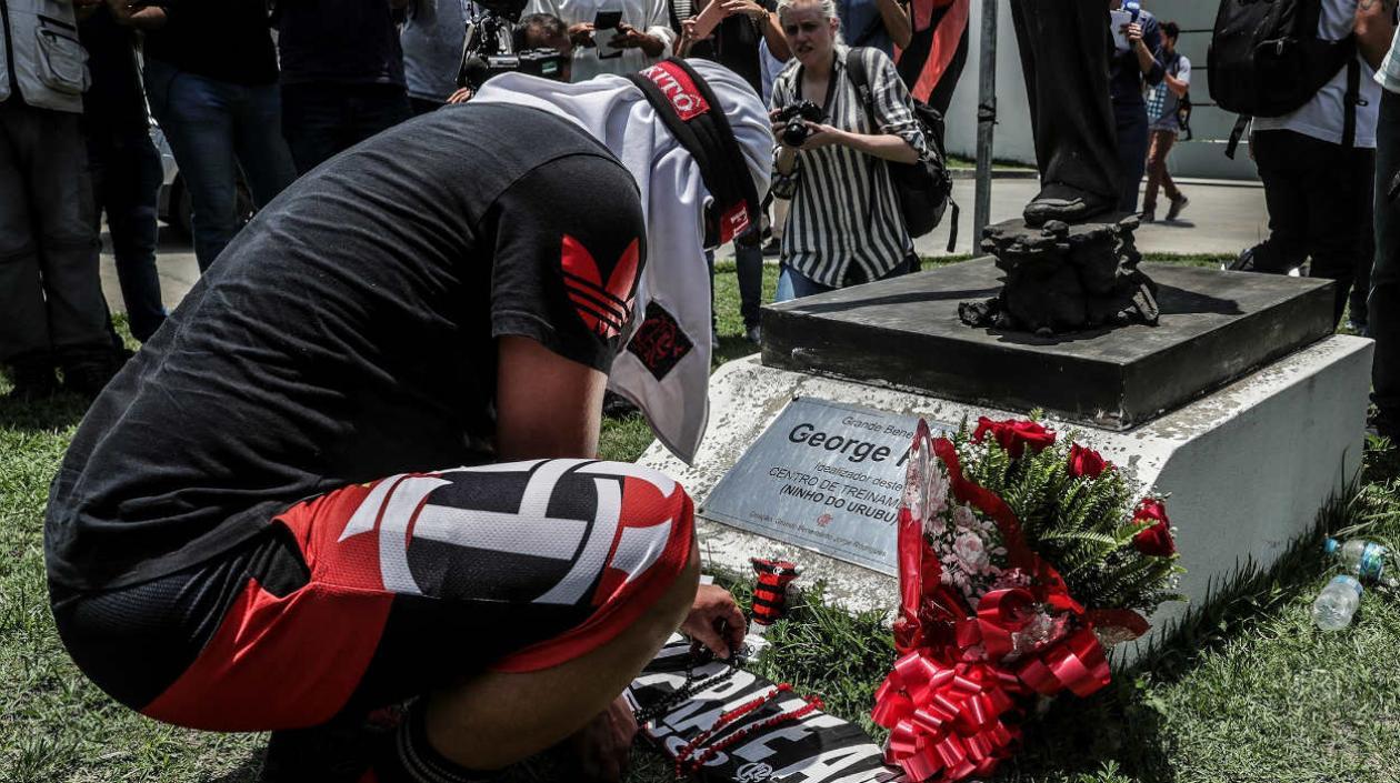 Un hombre pone flores en homenaje a las víctimas del incendio registrado en la madrugada de este viernes, en el centro de entrenamiento del club de fútbol Flamengo.