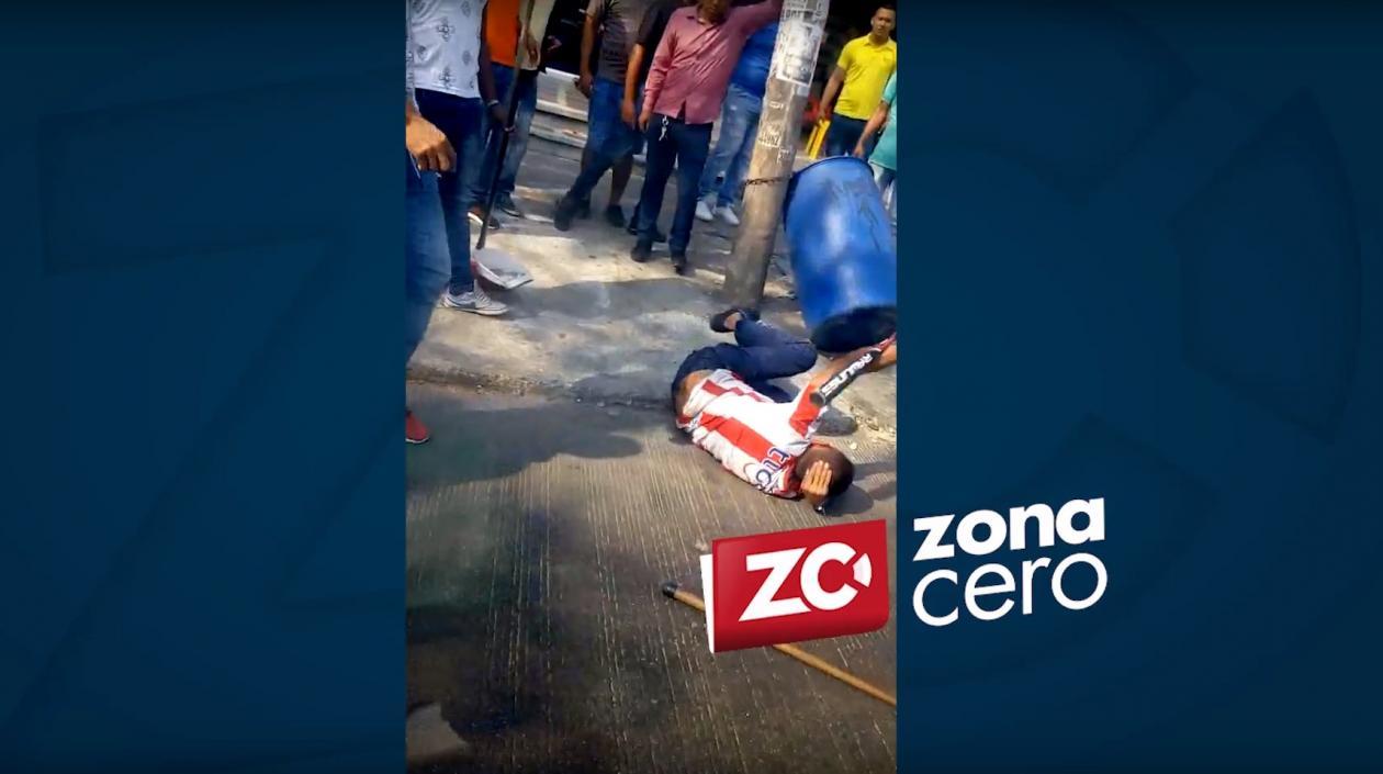 El presunto atracador, tras ser bajado del bus y golpeado.