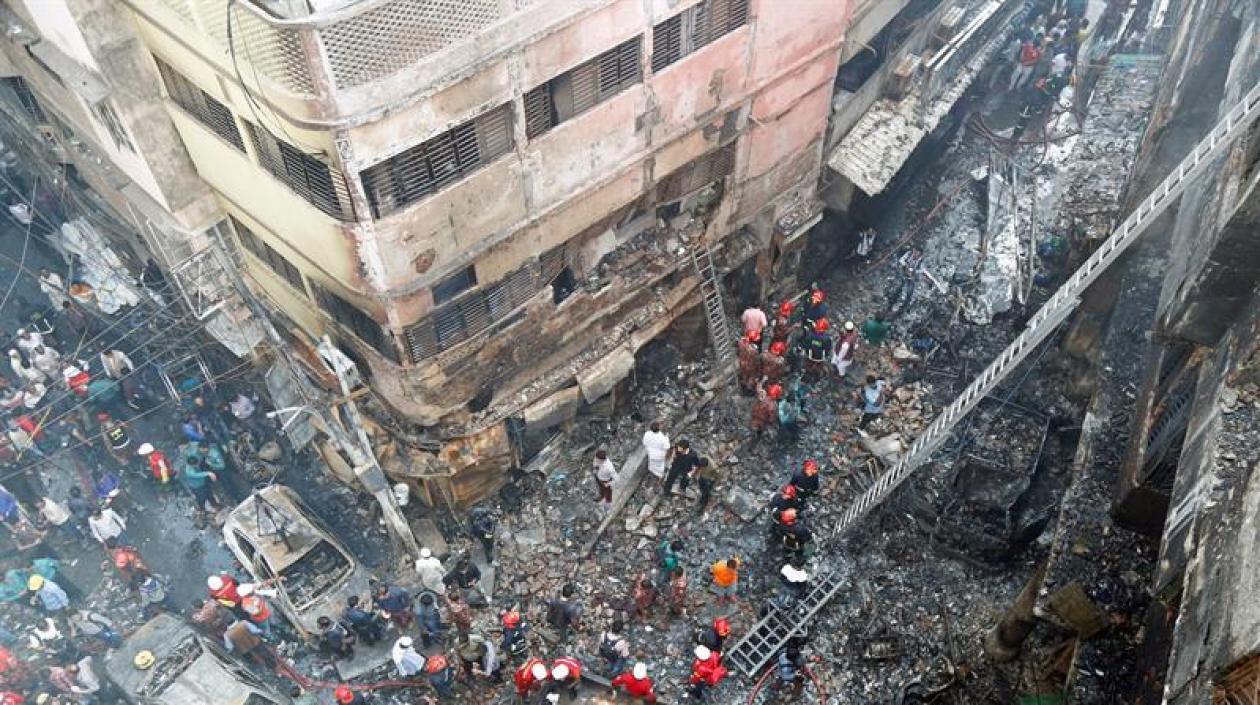 Varios bomberos inspeccionan los escombros tras el incendio declarado en la madrugada de este jueves en el barrio Chawkbazar del casco viejo de Dacca (Bangladesh).