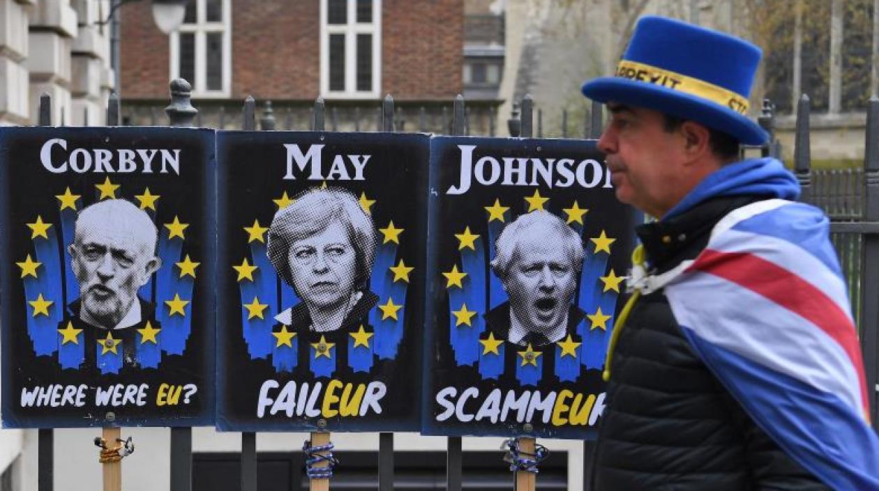 Un manifestante a favor de la estancia del Reino Unido en la Unión Europea camina, este martes, junto a carteles que critican a Jeremy Corbyn (i), Theresa May y Boris Johnson en Londres (Reino Unido). 