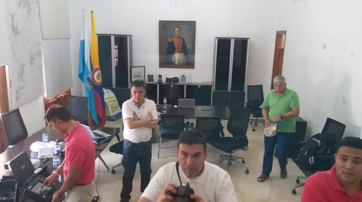 A la derecha, de rojo, Emiro Castro acompañado por otras 4 personas, mientras hacen revisiones de los discos duros. 