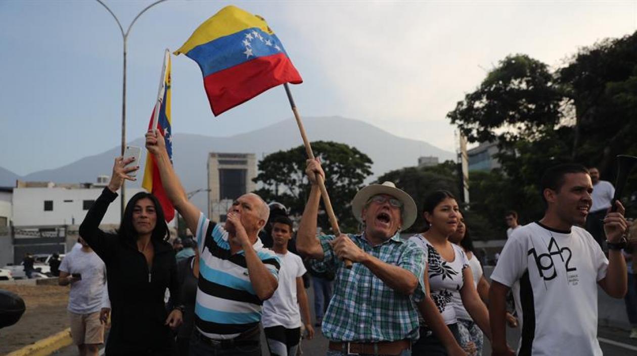 Simpatizantes del presidente interino Juan Guaidó ondean banderas este martes en la base militar La Carlota, donde se encuentra el presidente interino Guaidó y un grupo de militares que le apoyan. 