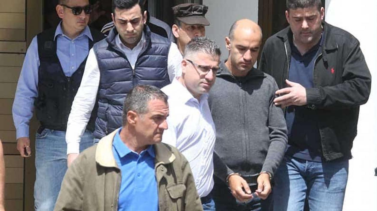 Nikos Metaxas es llevado esposado a la corte.