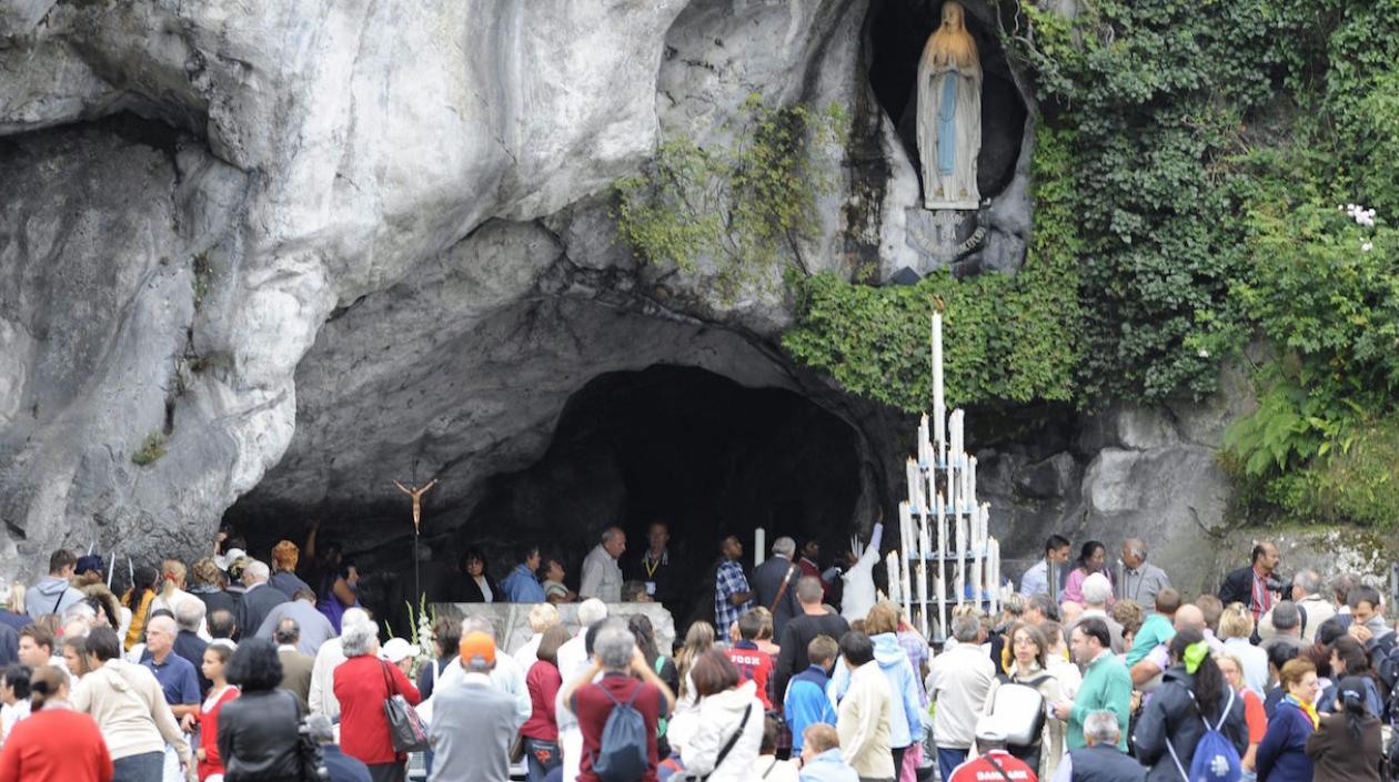 Peregrinos visitan la gruta donde supuestamente apareció la virgen en Lourdes, Francia.