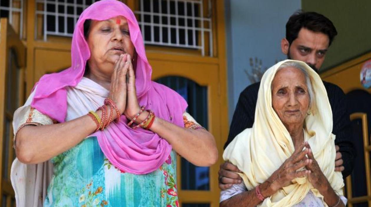 La mujer (i) y la madre de dos de los acusados de violar y asesinar a una niña de ocho años rezan antes del veredicto final, este lunes en Kathua (India). 