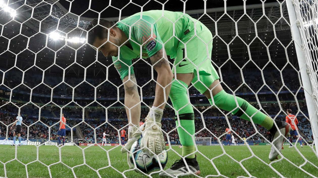 El arquero de Chile Gabriel Arias recoge el balón después de recibir un gol durante el partido Chile-Perú.