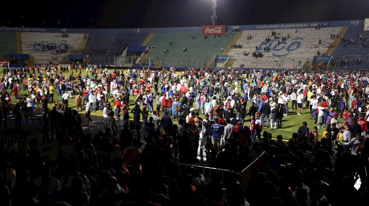 Aficionados ingresan al campo y se protegen de los gases lacrimógenos lanzados por las autoridade